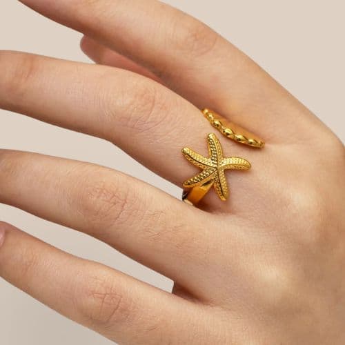 Bague ouverte devant étoile de mer et coquillage